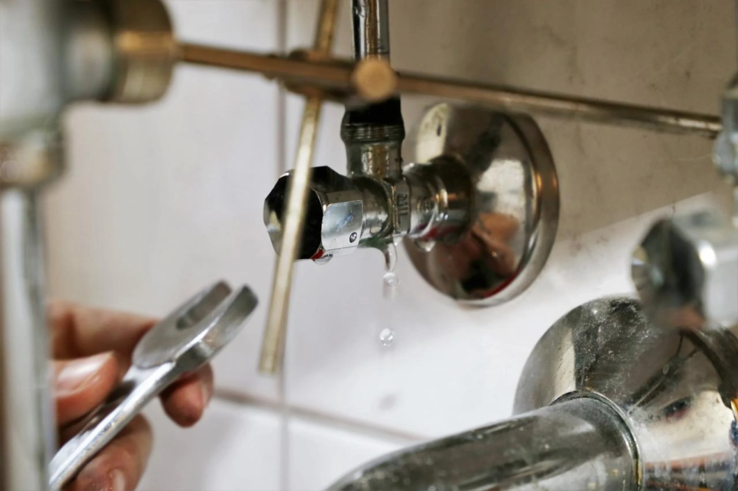 Plumber repairing a leaking water connection beneath a sink in Emerald, Queensland.